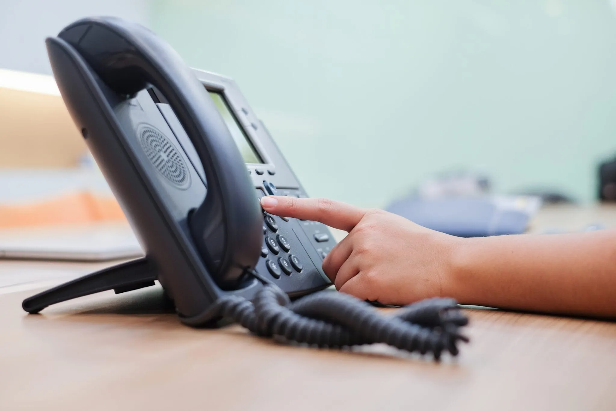 Person pressing buttons on office desk telephone for business communication