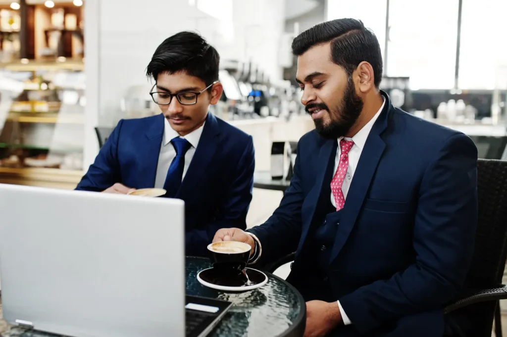 two-indian-businessmen-sitting-office-cafe-laptop-coffee-unified-voice